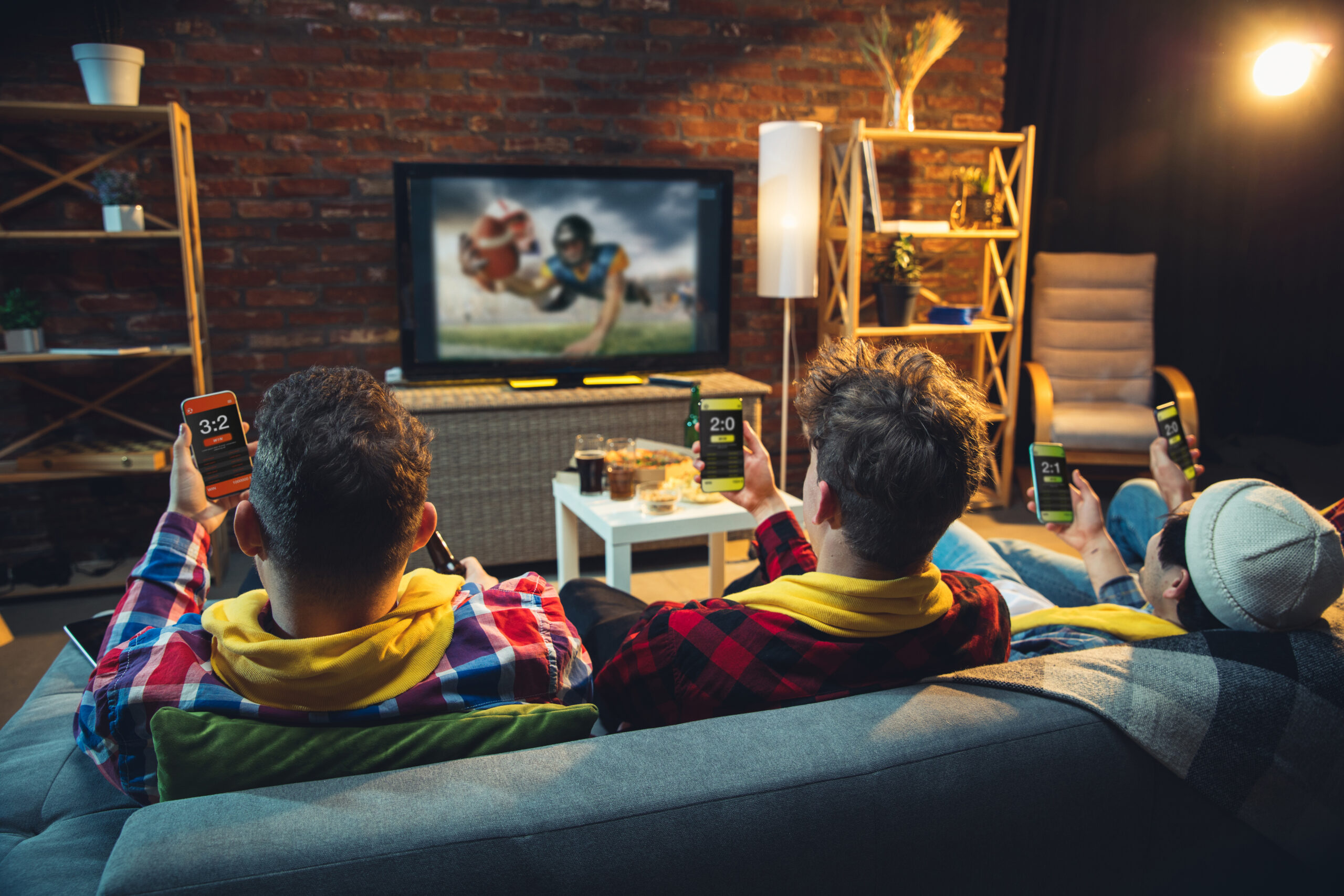 Group of friends watching TV, sport match together. Emotional fans cheering for favourite team, watching exciting football. Concept of friendship, leisure activity, emotions. Betting, finance, fun.